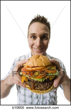 Portrait of a young man holding a hamburger and smiling View Large Photo Image Stock Photography - Portrait of a young man holding a hamburger and smiling. Fotosearch
