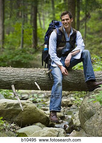 Portrait of a young man sitting on a fallen tree View Large Photo Image Stock Photography - Portrait of a young man sitting on a fallen tree. Fotosearch