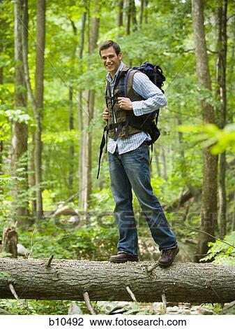 Portrait of a young man standing on a fallen tree View Large Photo Image Stock Image - Portrait of a young man standing on a fallen tree. Fotosearch