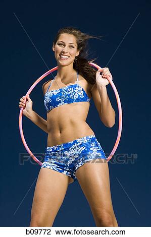 Portrait of a young woman holding a hula hoop and smiling View Large Photo Image Stock Image - Portrait of a young woman holding a hula hoop and smiling. Fotosearch