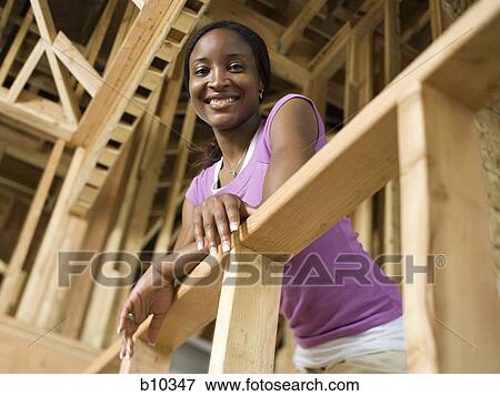 Stock Photo - Portrait of a young woman leaning against a railing and smiling. Fotosearch