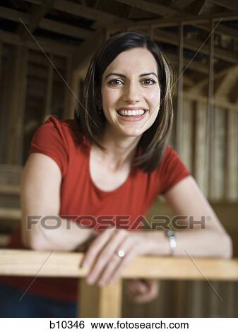 Portrait of a young woman leaning against a railing and smiling View Large Photo Image Stock Photograph - Portrait of a young woman leaning against a railing and smiling. Fotosearch