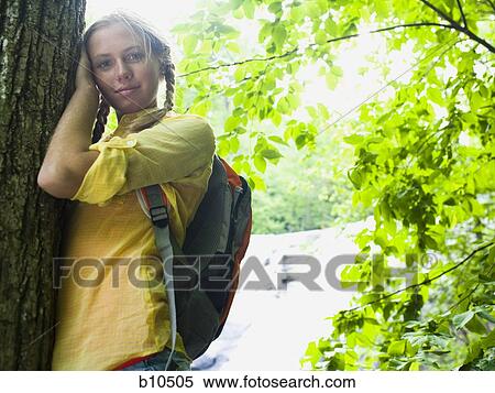 Portrait of a young woman leaning against a tree trunk View Large Photo Image Stock Photography - Portrait of a young woman leaning against a tree trunk. Fotosearch