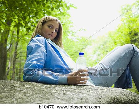 Portrait of a young woman lying on a rock and holding a water bottle View Large Photo Image Stock Image - Portrait of a young woman lying on a rock and holding a water bottle. Fotosearch