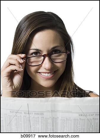 Portrait of a young woman reading a newspaper and peeking over her eyeglasses View Large Photo Image Stock Photo - Portrait of a young woman reading a newspaper and peeking over her eyeglasses. Fotosearch