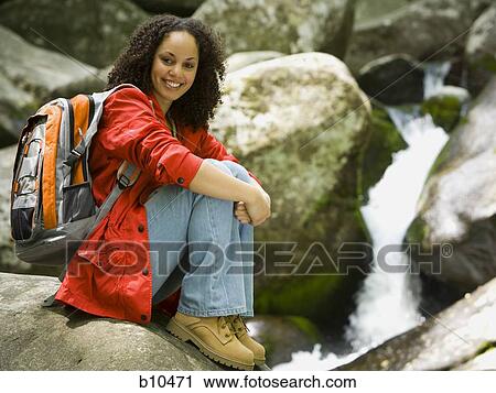 Portrait of a young woman sitting on a rock and smiling View Large Photo Image Stock Image - Portrait of a young woman sitting on a rock and smiling. Fotosearch
