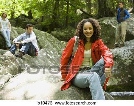 Portrait of a young woman sitting on a rock and smiling View Large Photo Image Stock Image - Portrait of a young woman sitting on a rock and smiling. Fotosearch