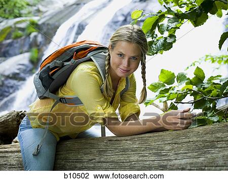 Portrait of a young woman sitting on a fallen tree View Large Photo Image Stock Image - Portrait of a young woman sitting on a fallen tree. Fotosearch