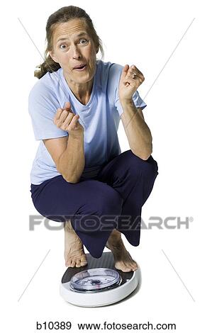 Stock Photo - Portrait of a young woman sitting on a scale. Fotosearch