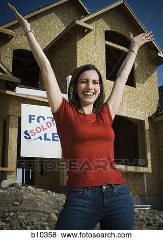 Portrait of a young woman smiling in front of a house View Large Photo Image Stock Photo - Portrait of a young woman smiling in front of a house. Fotosearch