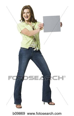 Portrait of a young woman standing and holding a blank sign View Large Photo Image Stock Photo - Portrait of a young woman standing and holding a blank sign. Fotosearch