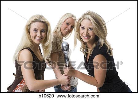 Portrait of three young women holding a microphone View Large Photo Image Stock Image - Portrait of three young women holding a microphone. Fotosearch
