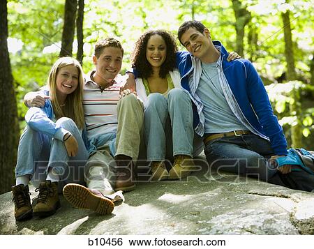Portrait of two young women and two young men sitting on a rock View Large Photo Image Stock Photograph - Portrait of two young women and two young men sitting on a rock. Fotosearch