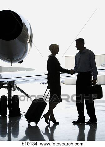 Profile of a businessman and a businesswoman shaking hands near an airplane View Large Photo Image Picture - Profile of a businessman and a businesswoman shaking hands near an airplane. Fotosearch