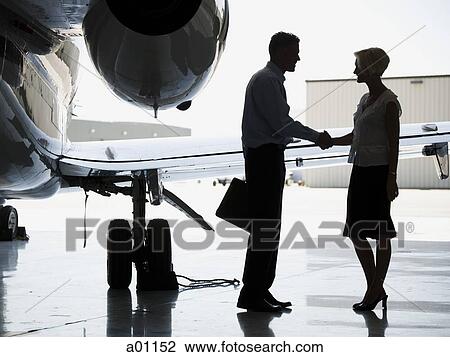Profile of a businessman and a businesswoman shaking hands by an airplane View Large Photo Image Stock Image - Profile of a businessman and a businesswoman shaking hands by an airplane. Fotosearch
