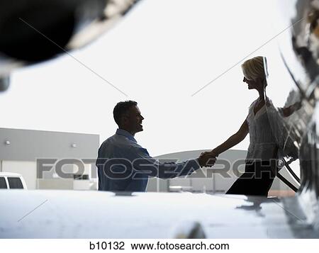 Profile of a businessman shaking hands with a businesswoman stepping down from an airplane View Large Photo Image Stock Image - Profile of a businessman shaking hands with a businesswoman stepping down from an airplane. Fotosearch