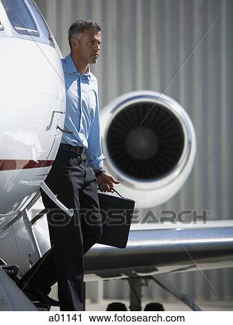 Stock Image - Profile of a businessman stepping down from an airplane. Fotosearch