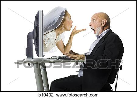 Stock Image - Profile of a senior woman blowing a kiss through a computer monitor to her groom. Fotosearch