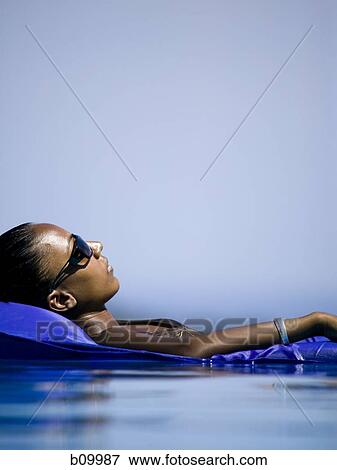 Profile of a young woman floating in water on an inflatable raft View Large Photo Image Stock Photo - Profile of a young woman floating in water on an inflatable raft. Fotosearch