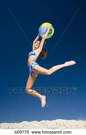 Profile of a young woman holding a beach ball and jumping View Large Photo Image Stock Photography - Profile of a young woman holding a beach ball and jumping. Fotosearch