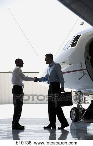Profile of two businessmen shaking hands near an airplane View Large Photo Image Stock Photograph - Profile of two businessmen shaking hands near an airplane. Fotosearch