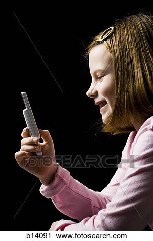 Stock Image - Profile of young girl with cellular phone smiling. Fotosearch