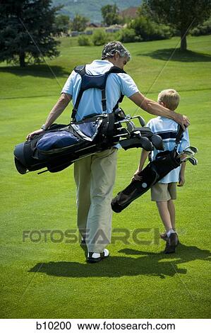 Stock Image - Rear view of a man carrying a golf bag with his son. Fotosearch