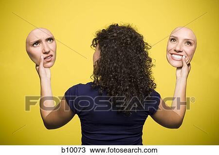 Rear view of a young woman holding cutouts of her face with two different expressions View Large Photo Image Stock Image - Rear view of a young woman holding cutouts of her face with two different expressions. Fotosearch