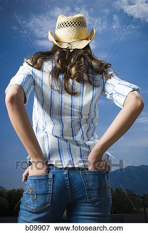 Rear view of a young woman standing with her hands in her pockets View Large Photo Image Stock Photo - Rear view of a young woman standing with her hands in her pockets. Fotosearch