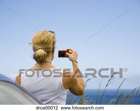 Rear view of a young woman taking a photograph with a digital camera View Large Photo Image Stock Image - Rear view of a young woman taking a photograph with a digital camera. Fotosearch