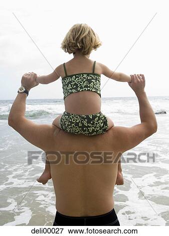 Stock Photo - Rear view of man giving piggy back ride to girl in bikini. Fotosearch