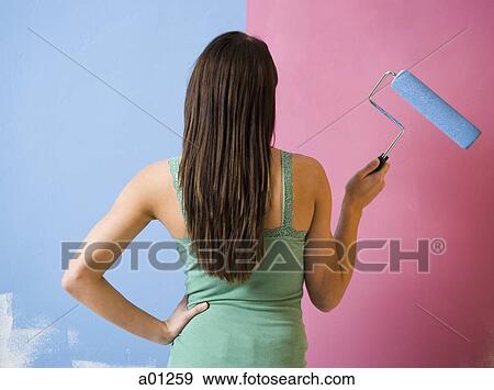Rear view of woman painting wall with a paint roller View Large Photo Image Stock Photo - Rear view of woman painting wall with a paint roller. Fotosearch