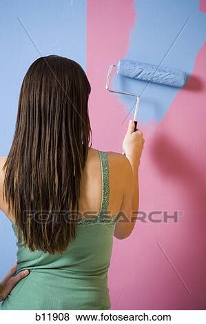 Rear view of woman painting wall with a paint roller View Large Photo Image Stock Photo - Rear view of woman painting wall with a paint roller. Fotosearch