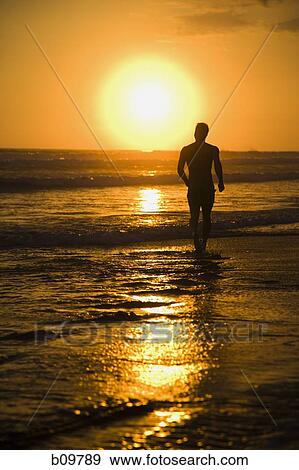 Silhouette of a person walking on the beach View Large Photo Image Stock Photo - Silhouette of a person walking on the beach. Fotosearch