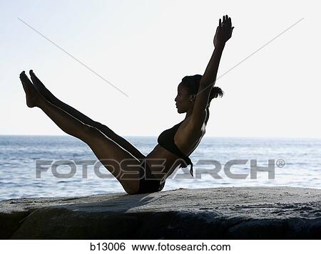 Stock Photograph - Silhouette of a woman exercising on a beach. Fotosearch