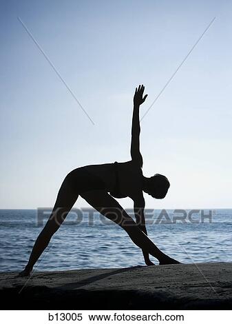 Stock Photography - Silhouette of a woman exercising on a beach. Fotosearch