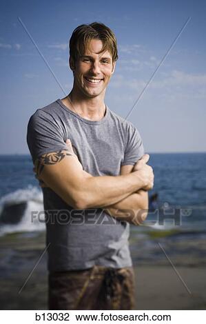 Stock Image - Smiling man on beach. Fotosearch