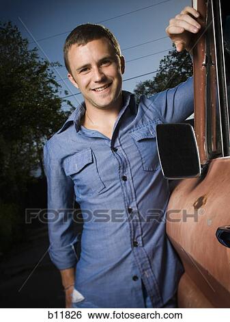 Stock Photograph - Smiling man standing beside old truck. Fotosearch