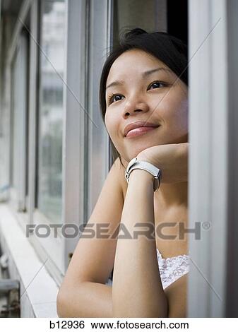 Stock Photograph - Smiling woman looking out a window. Fotosearch