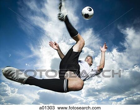 Soccer player kicks ball while silhouetted against a cloudy blue sky View Large Photo Image Stock Image - Soccer player kicks ball while silhouetted against a cloudy blue sky. Fotosearch