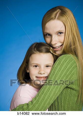 Teenage girl and young girl hugging View Large Photo Image Stock Image - Teenage girl and young girl hugging. Fotosearch