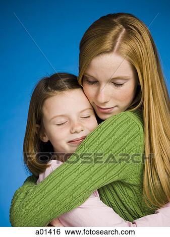 Teenage girl hugging young girl View Large Photo Image Stock Photograph - Teenage girl hugging young girl. Fotosearch