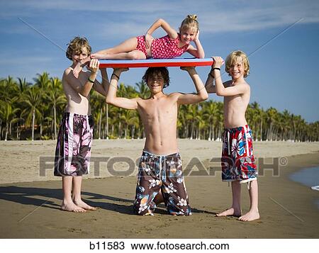 Stock Image - Three boys and sister playing on a beach. Fotosearch