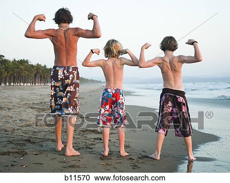 Stock Image - Three boys playing on beach. Fotosearch