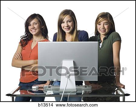 Picture - Three girls standing behind computer monitor smiling. Fotosearch