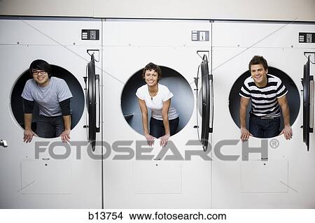 Three people in Laundromat dryers smiling View Large Photo Image Picture - Three people in Laundromat dryers smiling. Fotosearch