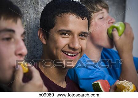 Stock Photo - Three teenage boys eating fruit. Fotosearch