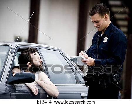 Picture - Traffic cop writing ticket to male driver with cigarette. Fotosearch