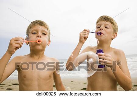 Stock Photography - Two boys blowing bubbles on the beach. Fotosearch