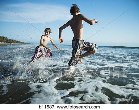 Two boys on beach running in surf View Large Photo Image Stock Photo - Two boys on beach running in surf. Fotosearch